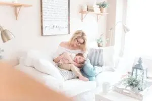 Mother and son sitting on a white couch embracing and playing.
