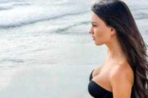 Woman in a strapless black bikini top on the beach.
